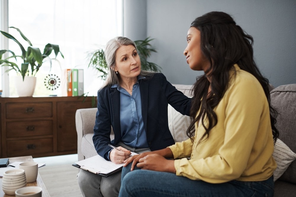 An image of a therapist and a client sitting on a couch together.